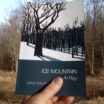 Holding a copy of Ice Mountain against the trees