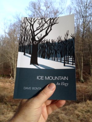 Holding a copy of Ice Mountain against the trees