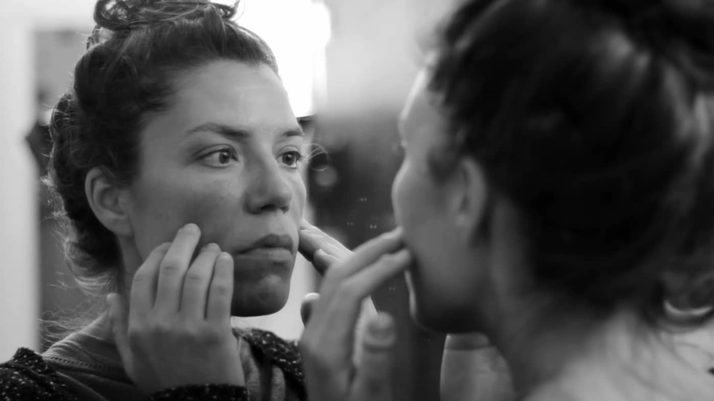 screenshot from Estado Fallido showing a woman examining her face in the mirror